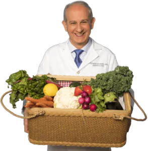 Stephen Devries, MD, wearing a white physician's coat and holding a large basket of colorful vegetables