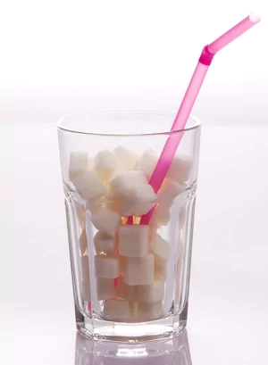 A drinking glass full of sugar cubes, with a straw inserted in it